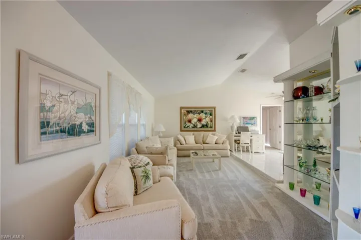 Carpeted living area with vaulted ceiling and ceiling fan