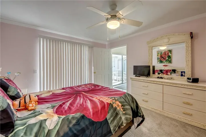 Carpeted bedroom featuring ornamental molding and a ceiling fan