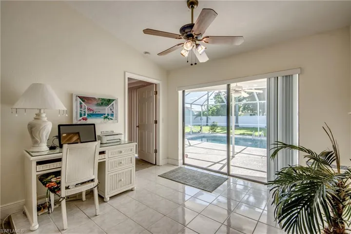Home office with a ceiling fan, vaulted ceiling, light tile patterned floors, and a sunroom