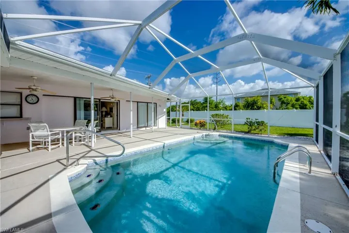 View of pool featuring a patio area, a ceiling fan, and glass enclosure