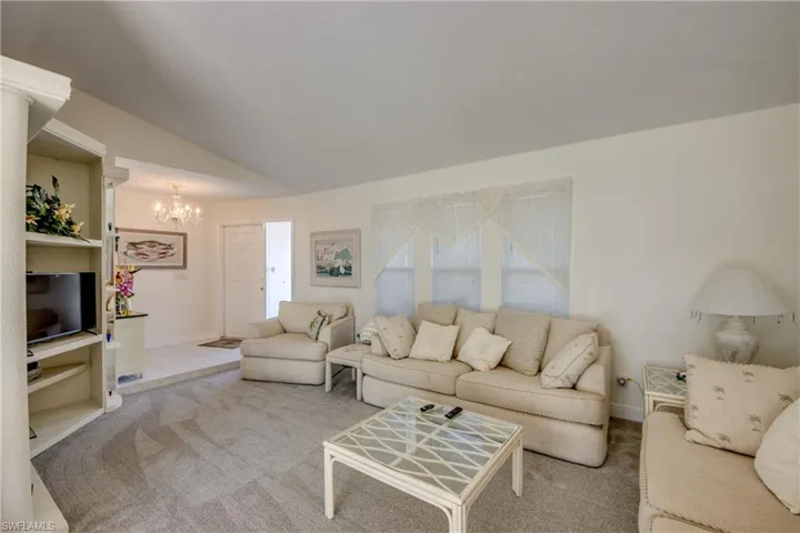 Carpeted living room featuring a chandelier and lofted ceiling