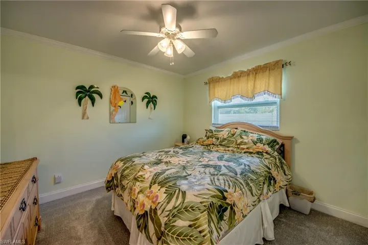 Carpeted bedroom featuring ornamental molding and ceiling fan