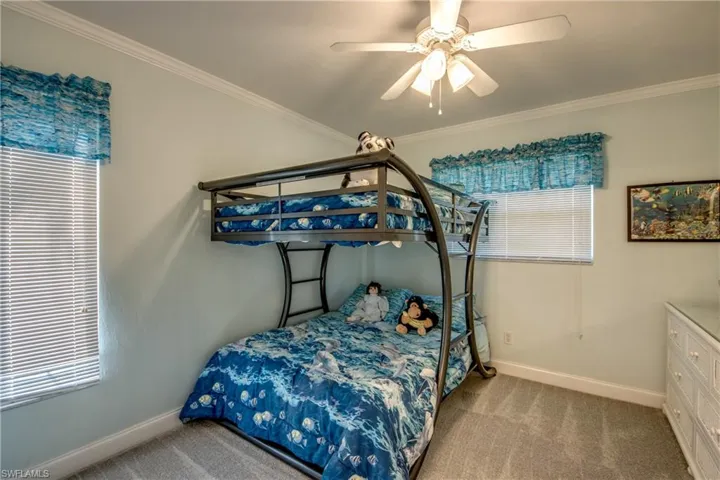 Carpeted bedroom featuring crown molding and ceiling fan