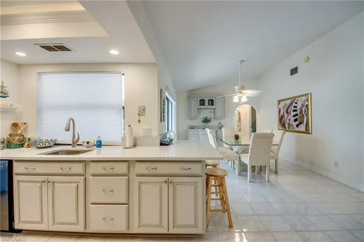 Kitchen with ceiling fan, cream cabinets, light countertops, and vaulted ceiling