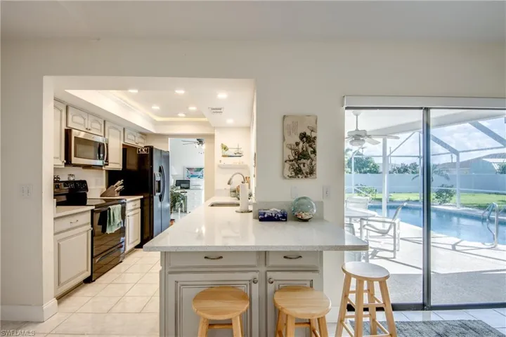 Kitchen featuring black appliances, a ceiling fan, a breakfast bar area, a peninsula, and crown molding