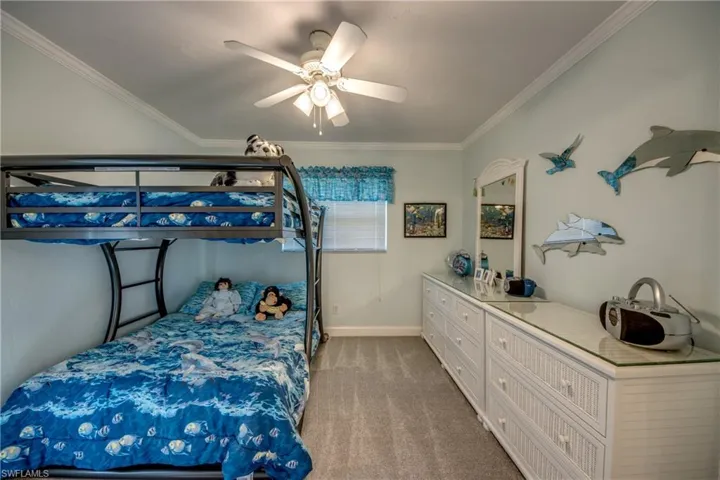 Carpeted bedroom featuring ornamental molding and ceiling fan