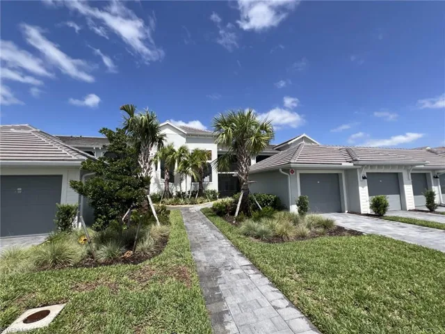 View of front of house featuring decorative driveway, a tile roof, an attached garage, stucco siding, and a front yard