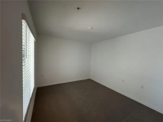 Empty room with dark carpet and baseboards