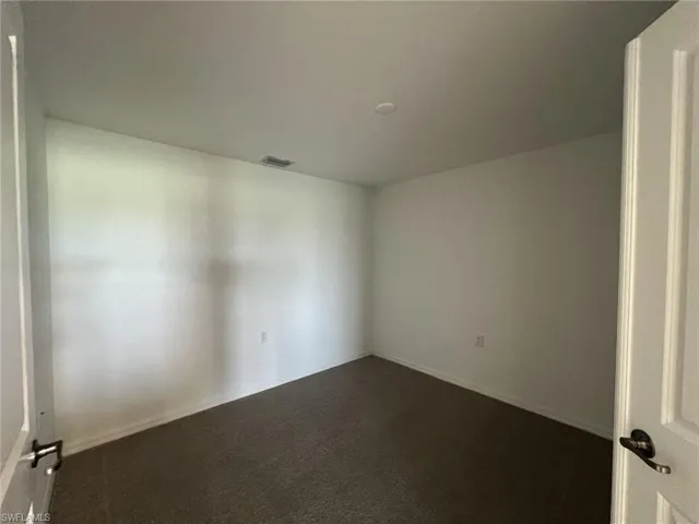 Den with dark colored carpet and baseboards