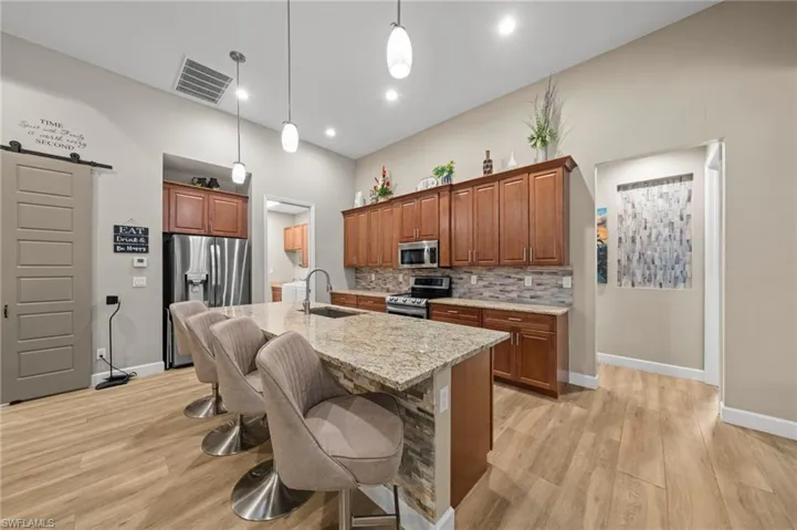 Kitchen with a barn door, a kitchen breakfast bar, appliances with stainless steel finishes, open floor plan, and brown cabinets