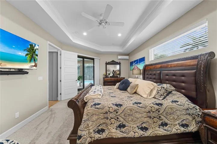 Bedroom featuring a tray ceiling, ornamental molding, light colored carpet, recessed lighting, and a ceiling fan