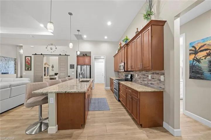 Kitchen featuring appliances with stainless steel finishes, light stone counters, and light wood finished floors