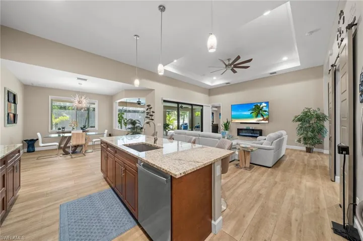 Kitchen with light wood-style flooring, decorative backsplash, appliances with stainless steel finishes, and decorative light fixtures