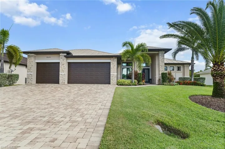 View of front of home featuring an attached garage, decorative driveway, stucco siding, and a front yard