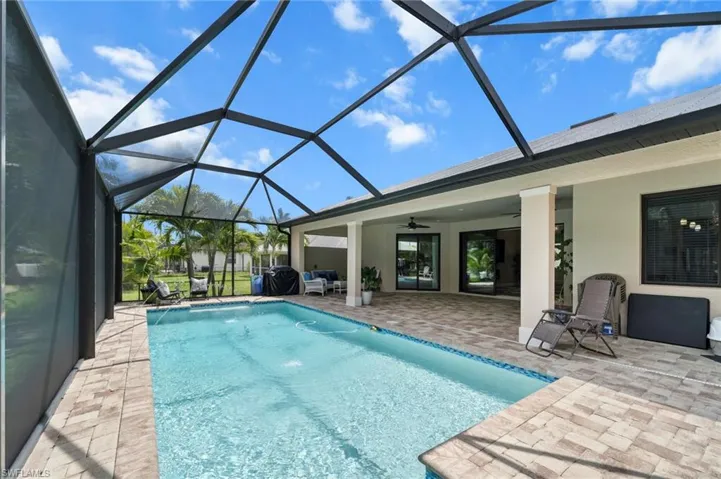 Swimming pool featuring a patio, ceiling fan, and glass enclosure