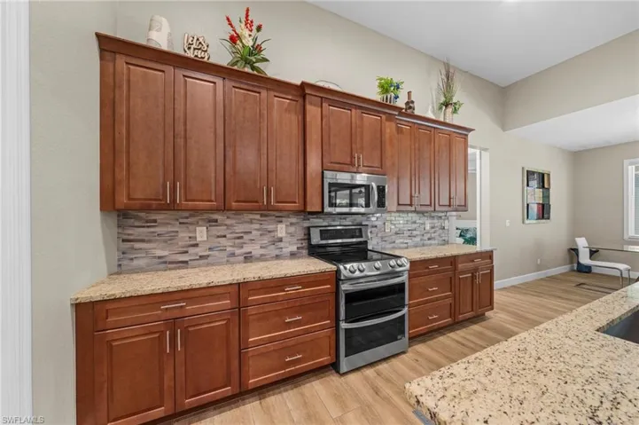 Kitchen featuring a barn door, dishwasher, light wood-style flooring, a ceiling fan, and light stone counters