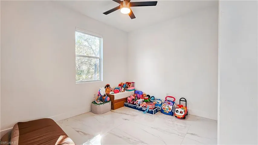Recreation room with marble look tile flooring and a ceiling fan