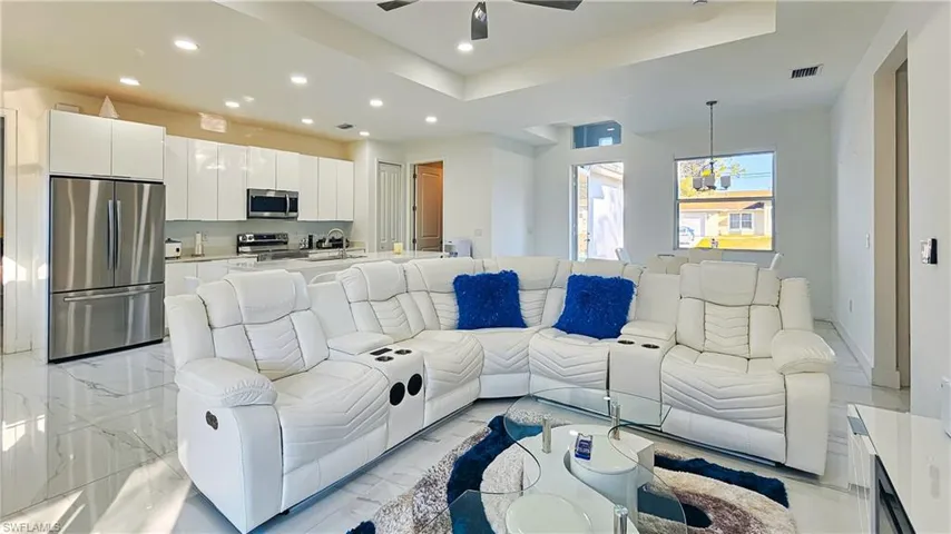 Living area with light marble finish flooring, recessed lighting, a raised ceiling, and ceiling fan