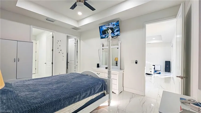 Bedroom featuring a tray ceiling, recessed lighting, marble finish flooring, and ceiling fan