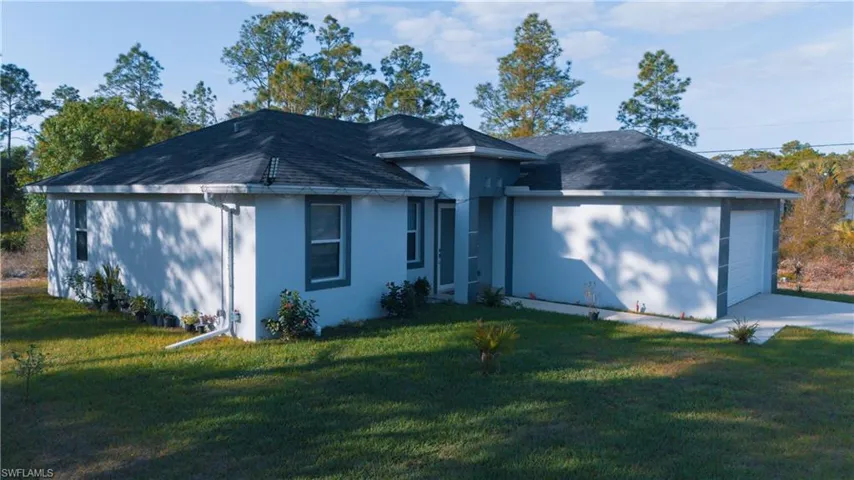 Ranch-style house with a garage, stucco siding, a front yard, and a shingled roof