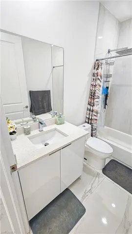 Bathroom featuring marble finish flooring, vanity, and shower / bath combination with curtain