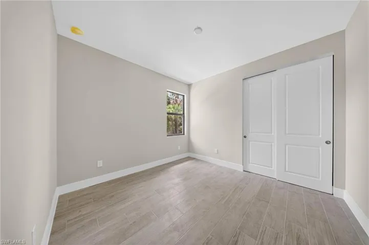 Room featuring wood-finish tile flooring, neutral wall paint, and white baseboards