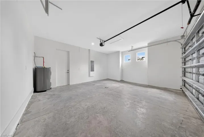 Spacious garage featuring a concrete floor, bright white walls, and a large roll-up garage door