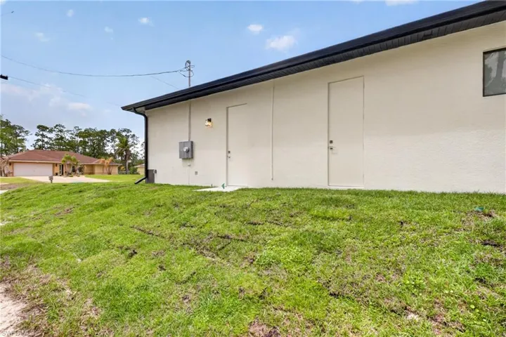 Exterior stucco wall featuring two entry doors, a single window, and a wall-mounted light fixture