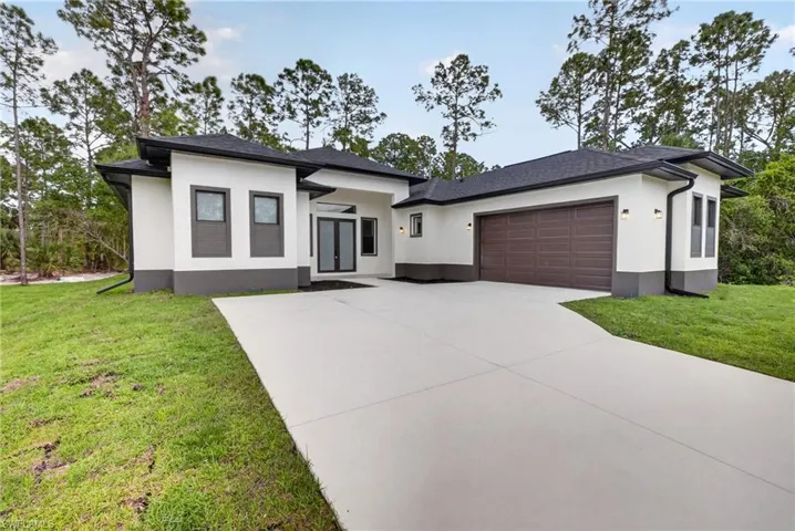 Contemporary exterior featuring a white stucco finish with dark gray accents, a dark shingle roof, a two-car garage with a panel door, a concrete driveway, and a double-door entry