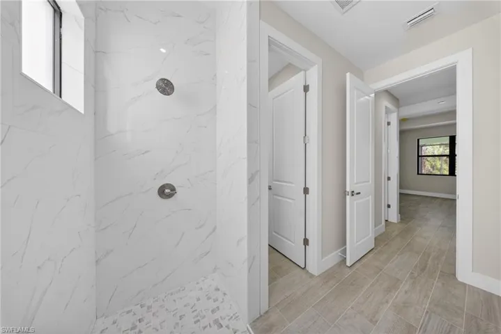 Tiled shower with a mosaic tile floor, two shower heads, and an integrated window
