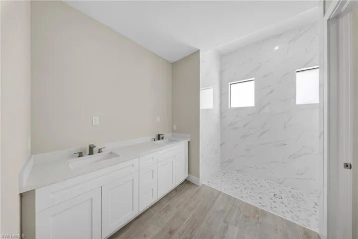 Spacious bathroom featuring a dual vanity with white cabinetry and light-toned countertops