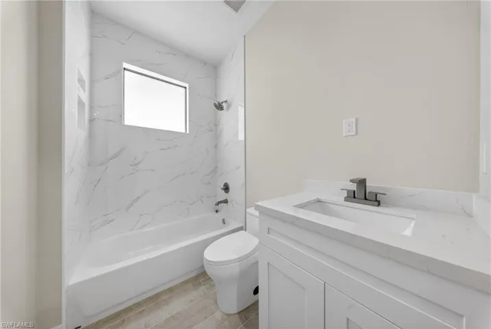 Bathroom featuring a white vanity with a quartz countertop, an undermount sink, and a matte black faucet