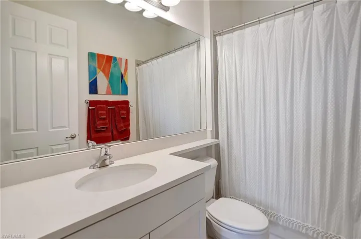 Bathroom featuring a shower with curtain, vanity, and toilet