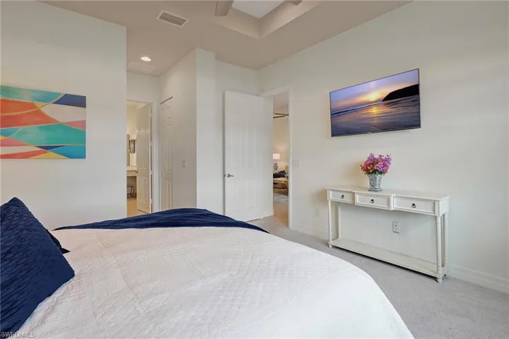 Carpeted bedroom featuring ensuite bathroom and ceiling fan