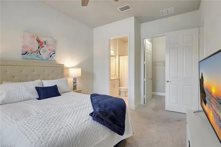 Bedroom featuring ensuite bath, ceiling fan, a closet, and light colored carpet