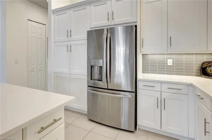Kitchen with white cabinets, light tile patterned flooring, and stainless steel refrigerator with ice dispenser