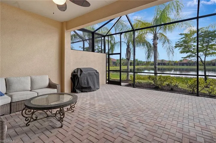 View of patio featuring a lanai, ceiling fan, a grill, and a water view