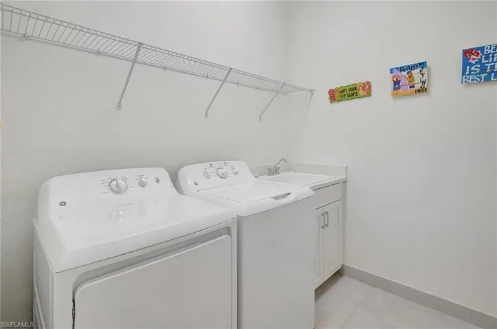 Laundry room with separate washer and dryer, sink, and cabinets