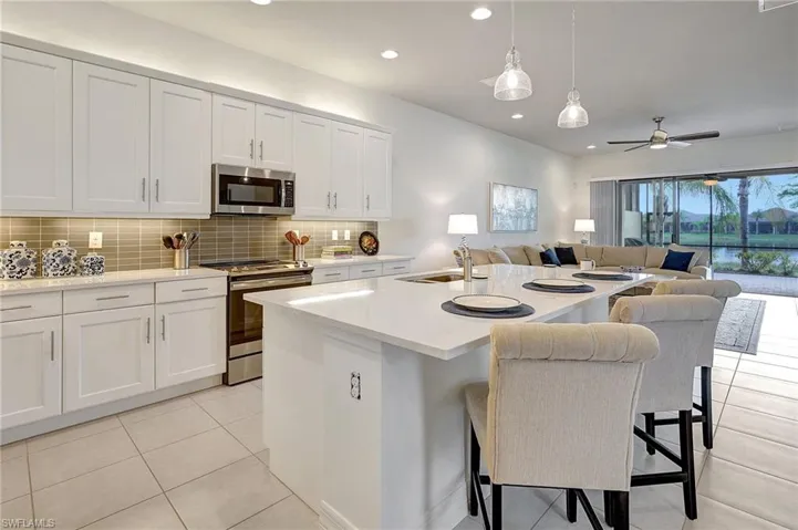 Kitchen featuring stainless steel appliances, sink, a center island with sink, white cabinets, and a breakfast bar area