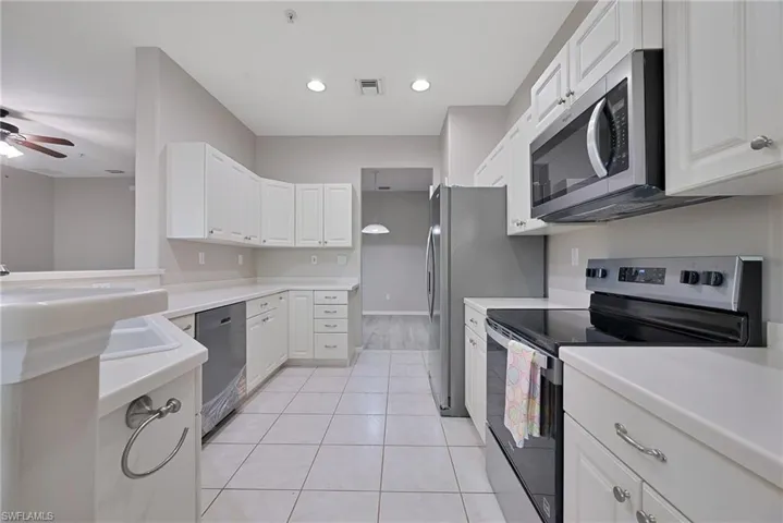 Never used stainless steel appliances, light countertops, white cabinetry, and a ceiling fan