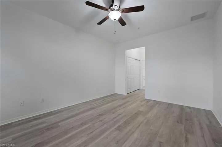 Large Primary Bedroom with ceiling fan, luxury vinyl floors, facing bath with double closets