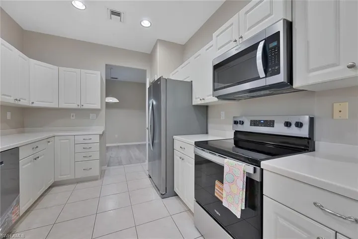 Kitchen featuring new stainless steel appliances, light countertops, white cabinetry, light tile patterned floors, and recessed lighting