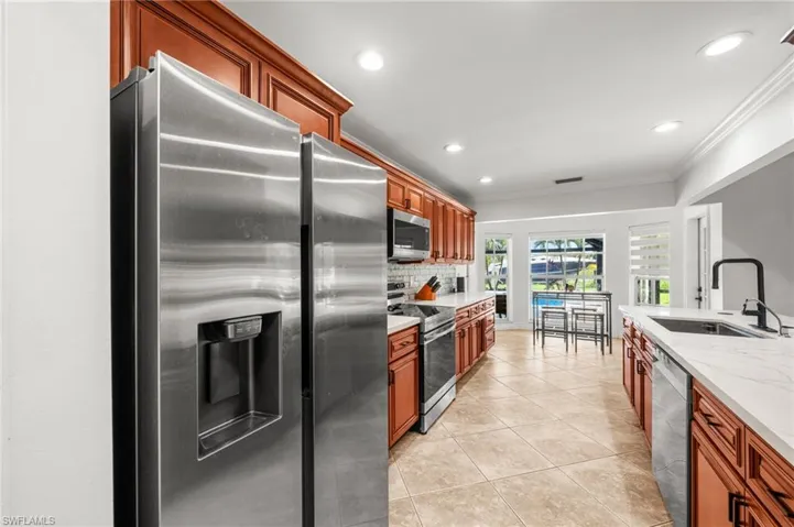Kitchen with appliances with stainless steel finishes, ornamental molding, decorative backsplash, light tile patterned floors, and recessed lighting