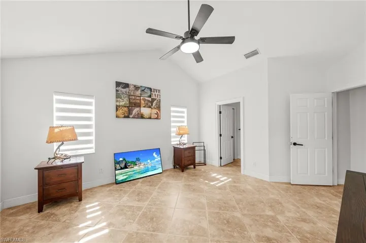 Living area featuring a ceiling fan, light tile patterned floors, and high vaulted ceiling