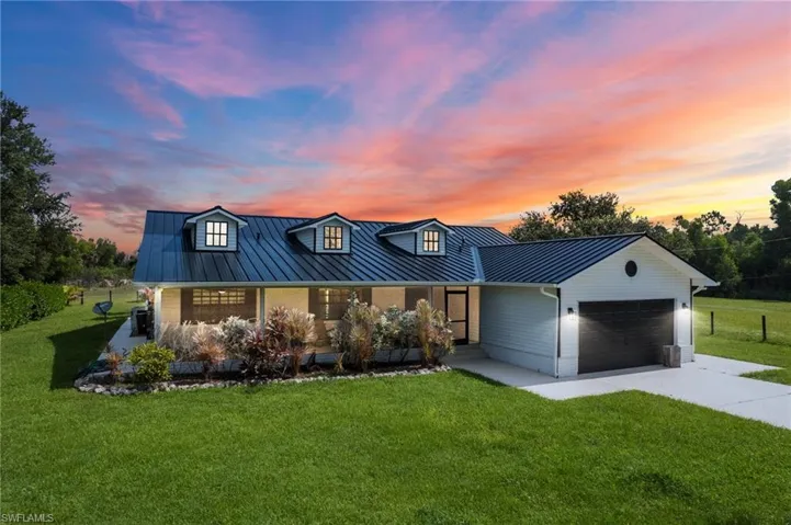 Modern inspired farmhouse with a garage, concrete driveway, a metal roof, and brick siding