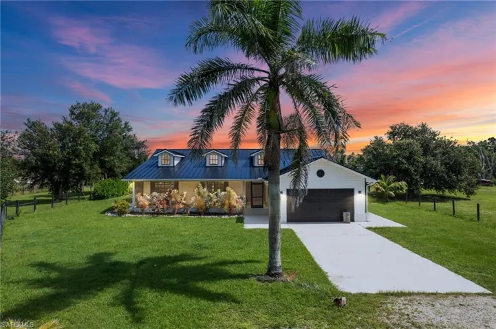 View of front of house featuring concrete driveway, an attached garage, and a metal roof