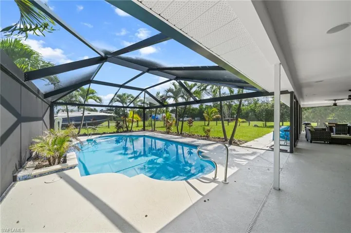 Swimming pool with a ceiling fan, a patio area, a lawn, and glass enclosure
