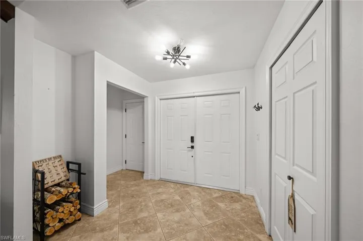 Foyer with light tile patterned floors and a chandelier