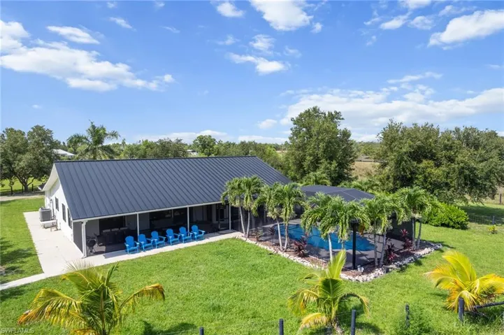 Rear view of property featuring a patio area, a metal roof, an outdoor pool, and a yard