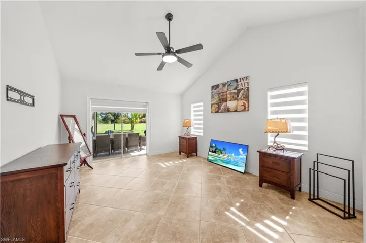 Living area with ceiling fan, high vaulted ceiling, and light tile patterned flooring